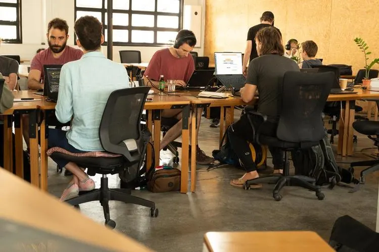 Developers working on laptops at shared tables in a co-working room
